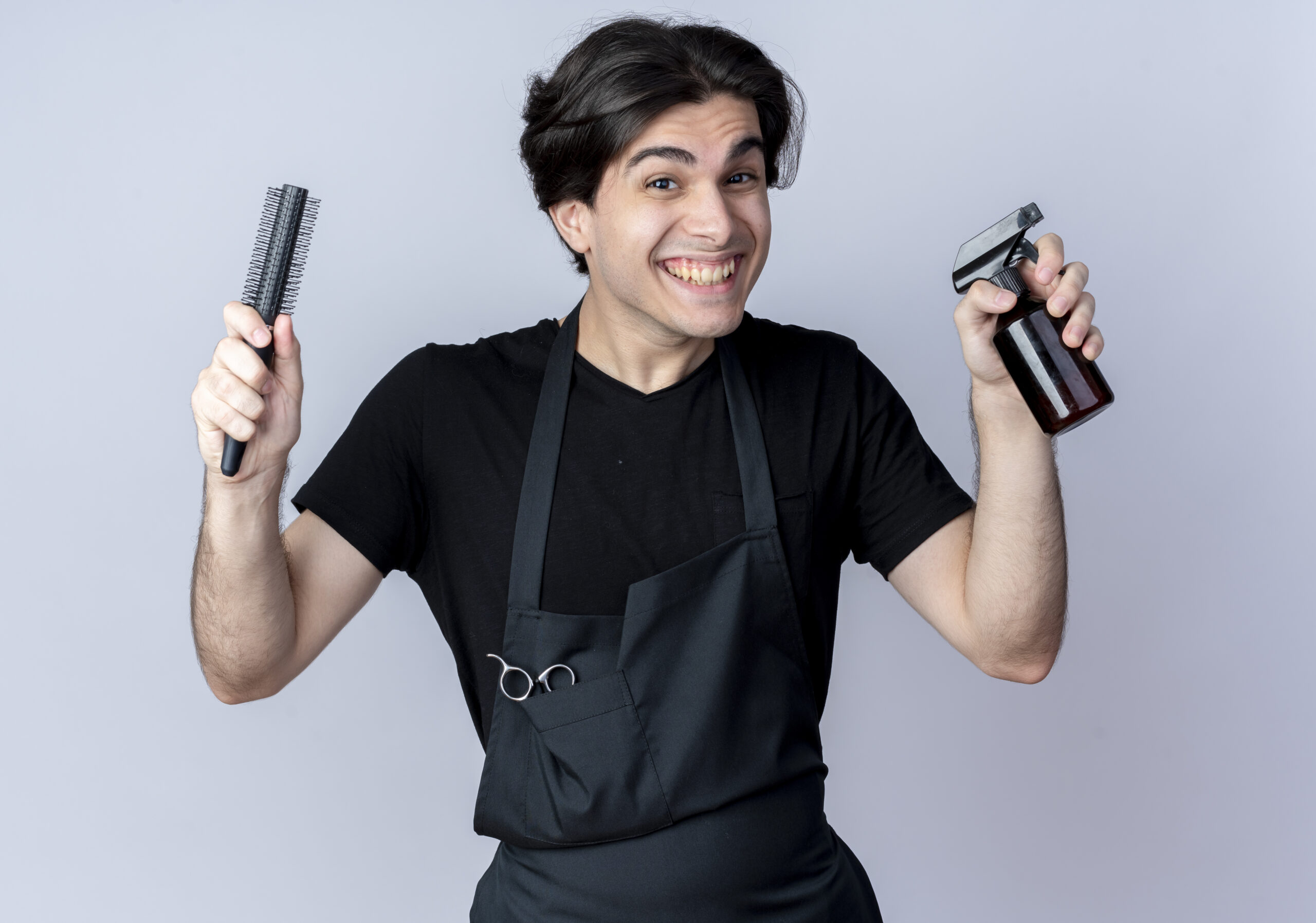 joyful young handsome male barber uniform holding comb with spray bottle isolated white background scaled